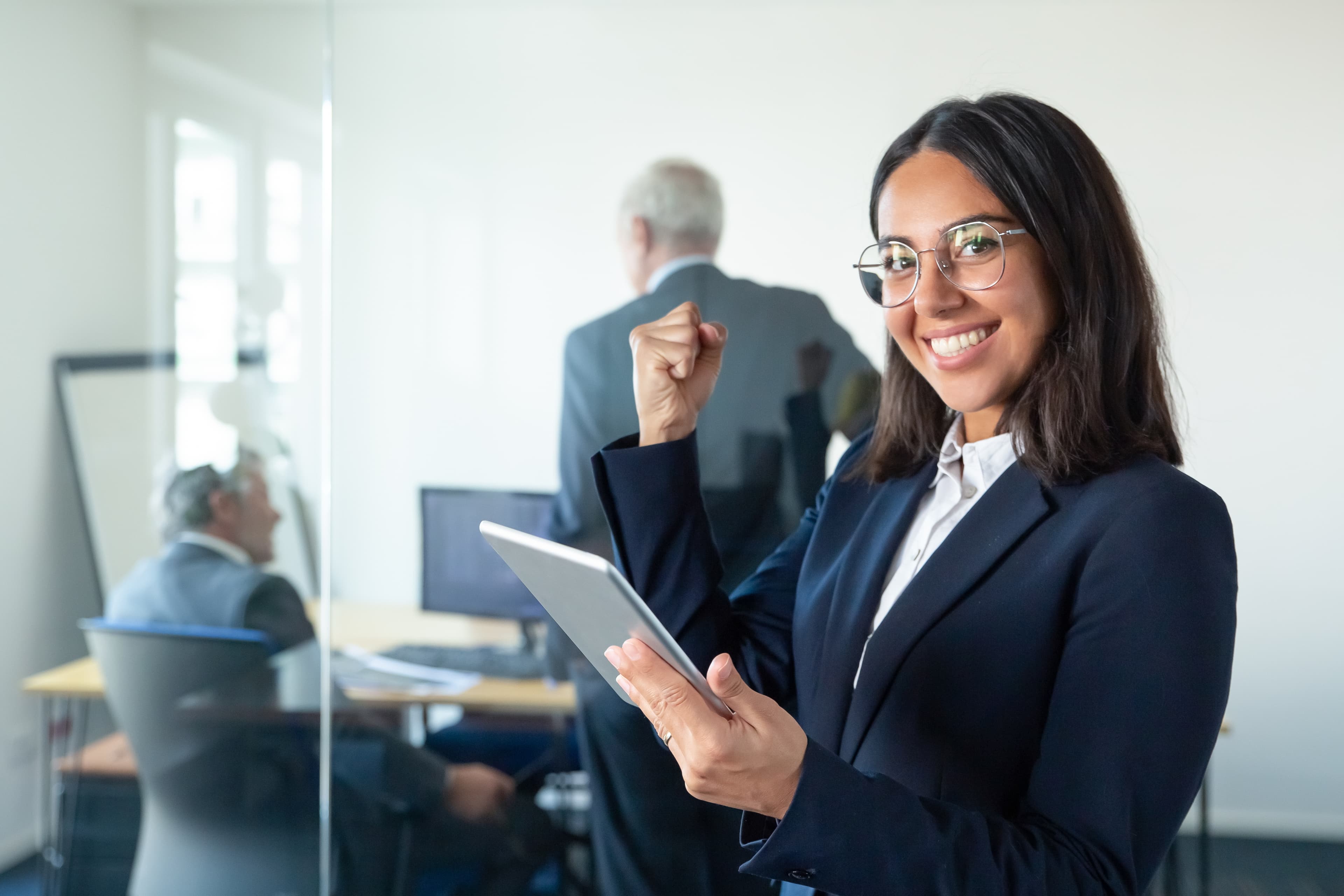 Profissional sorrindo com tablet em um ambiente de trabalho colaborativo